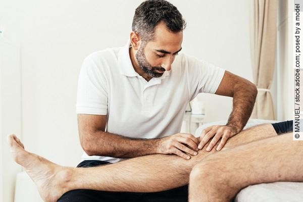 Therapeut behandelt Patienten am Knie.
