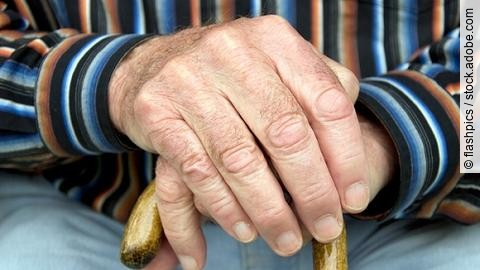 Senior stützt Hände auf Gehstock