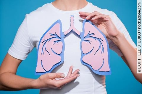 Frau hält Lunge aus Papier vor ihrem Brustkorb