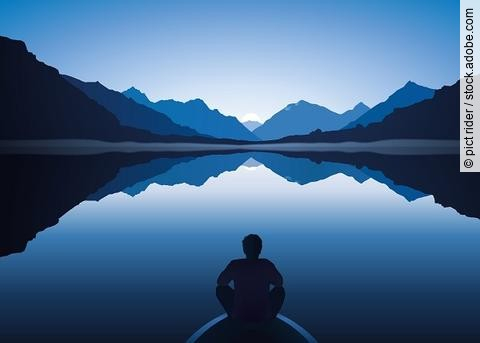 Mann sitzt auf Bootssteg am See von Bergen umgeben