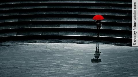 Mensch mit rotem Schirm bei Regen allein auf einer Treppe, Einsamkeit