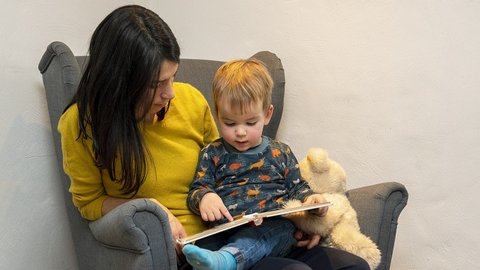 Mutter liest ihrem Kleinkind aus einem Buch vor