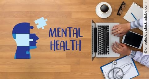 Umriss eines menschlichen Kopfs aus Puzzleteile, rechts daneben liegt ausgeschnitten das Wort mental health. Arzt sitzt am Tisch mit Arbeitsunterlagen.